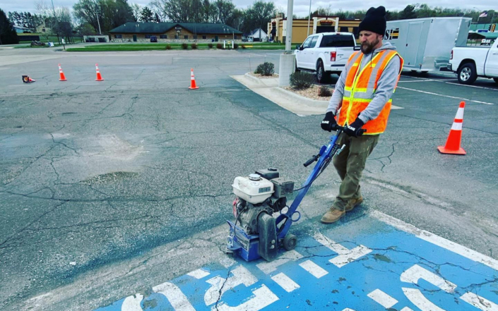Worker Removing Paint In Parking Lot