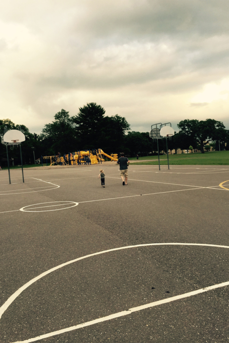 Man And Child In Lot With Several Basketball Courts
