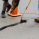 Person Using Tools To Fill Cracks In Asphalt Parking Lot
