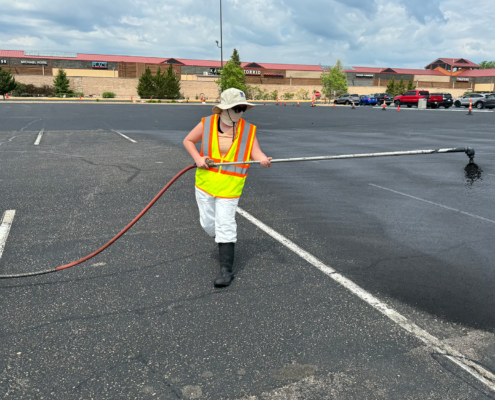 Woman Painting Seal Coating On Outlet Mall Parking Lot