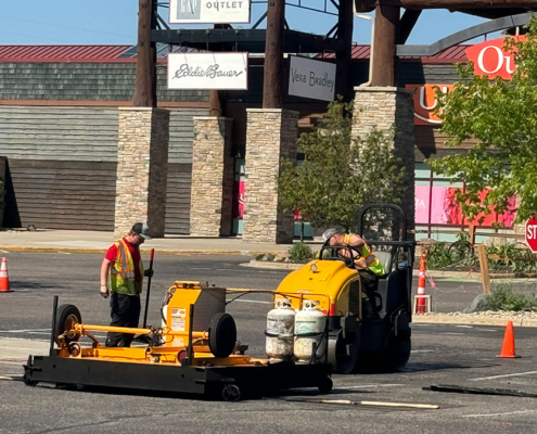 Workers Filling Pothole In Outlet Mall Parking Lot