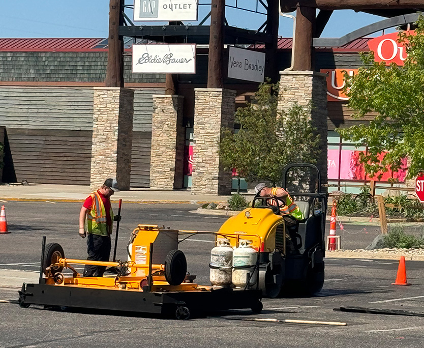 Workers Filling Pothole In Outlet Mall Parking Lot